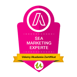 Rosafarbenes Abzeichen mit der Aufschrift „SEA Marketing Experte“ und gelbem Band mit der Aufschrift „Udemy Akademie Zertifikat“.